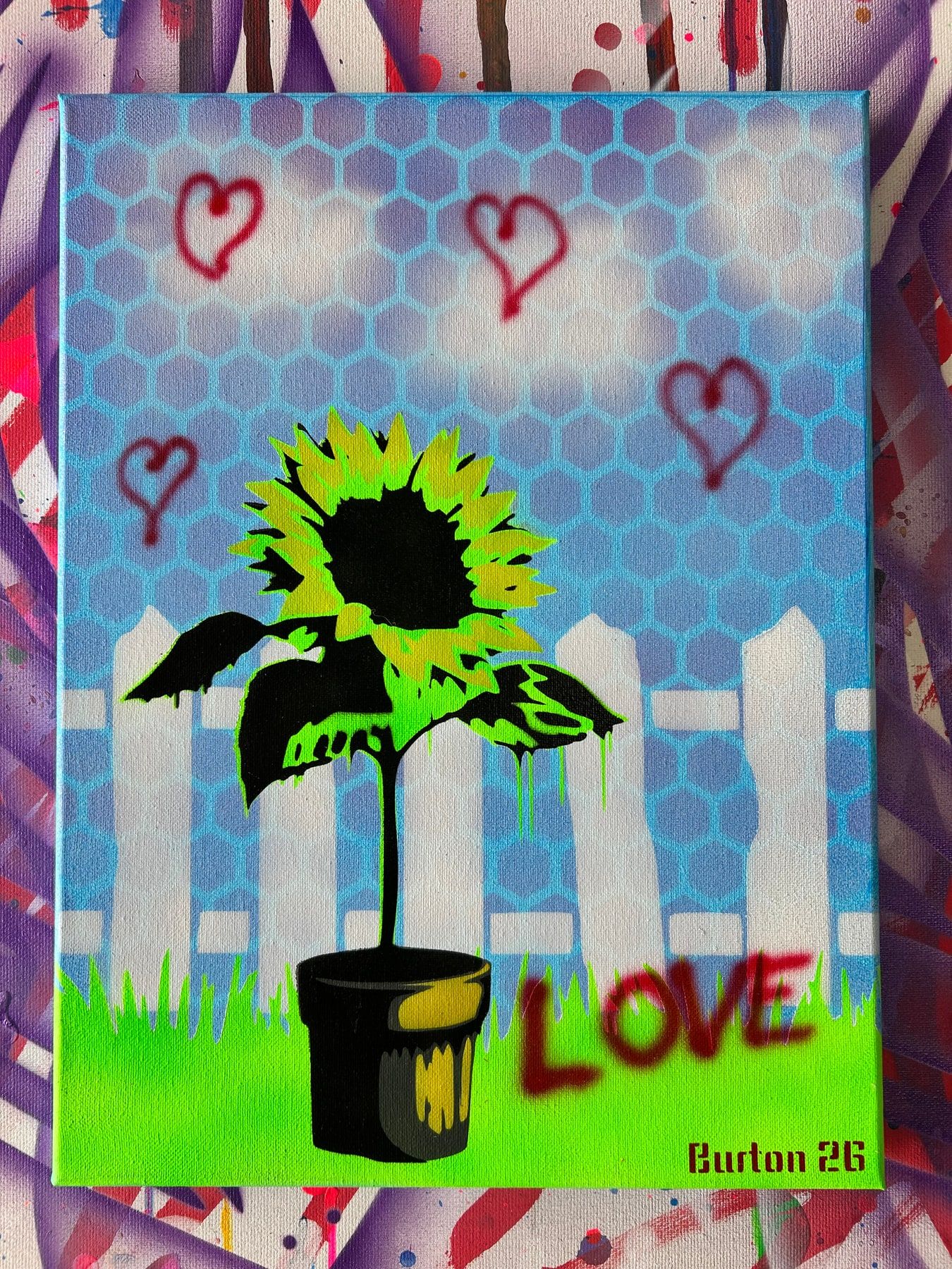 Stencil sunflower being painted by a spray-can roller, blue honeycomb background with red hearts and the word Love.